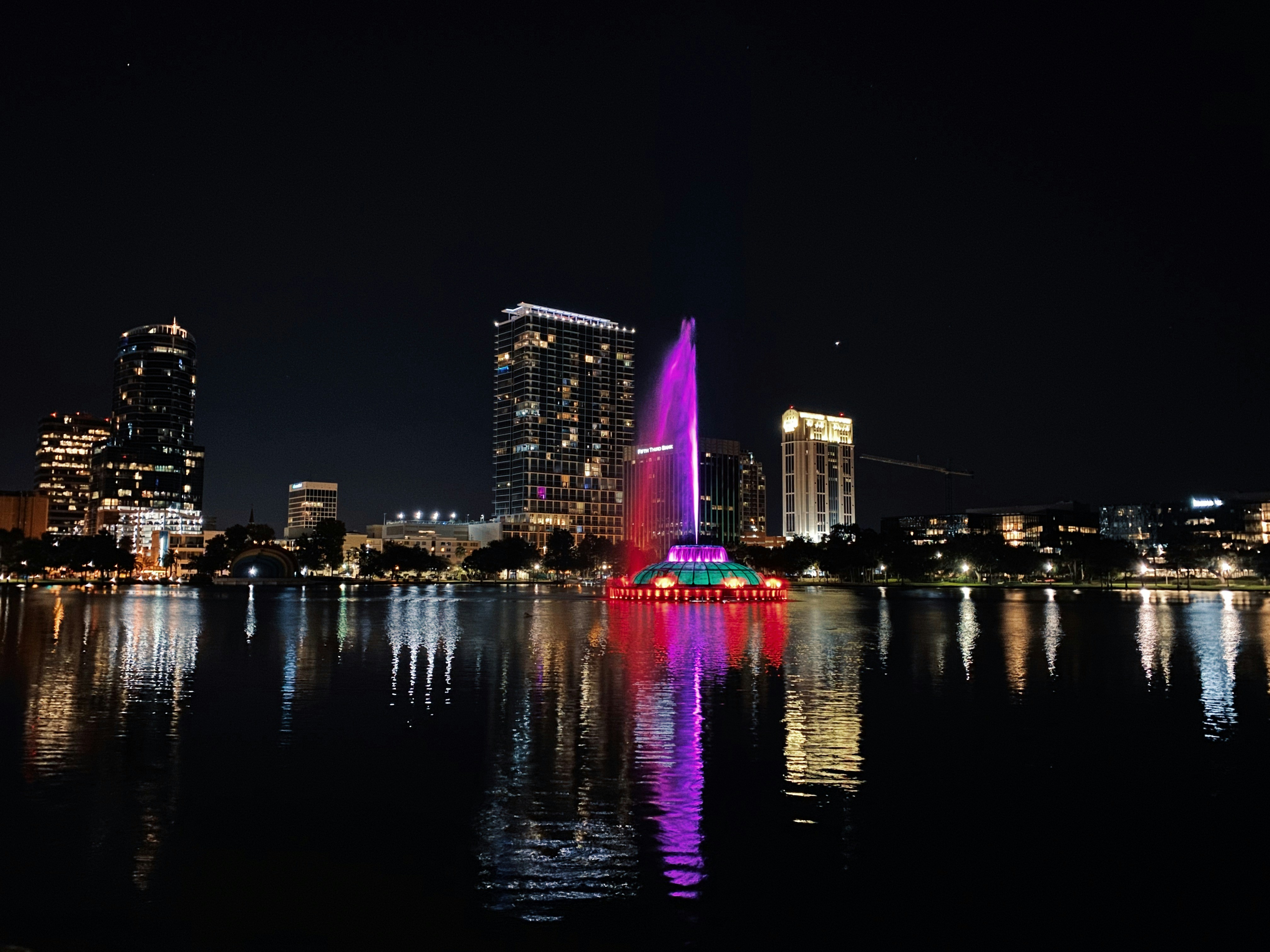 Orlando Lake Eola fountain illuminated at night with downtown skyline reflection